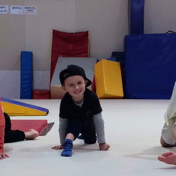 Young boy performing splits during springboard mini gymnastics session