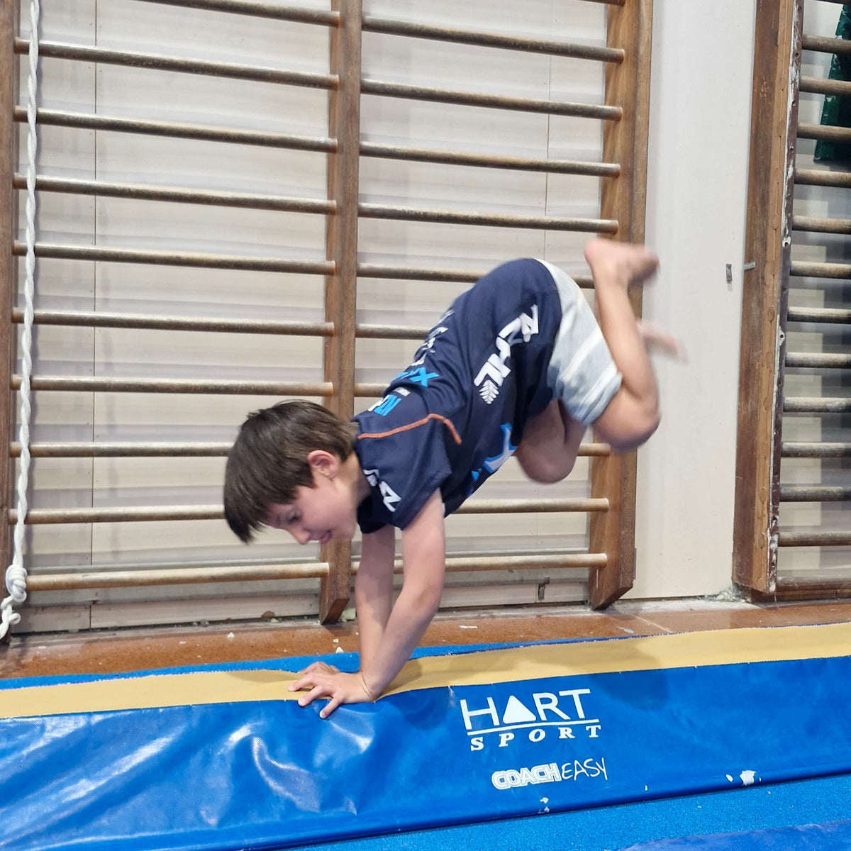 Boy performing bunny hop on beam at gymnastics