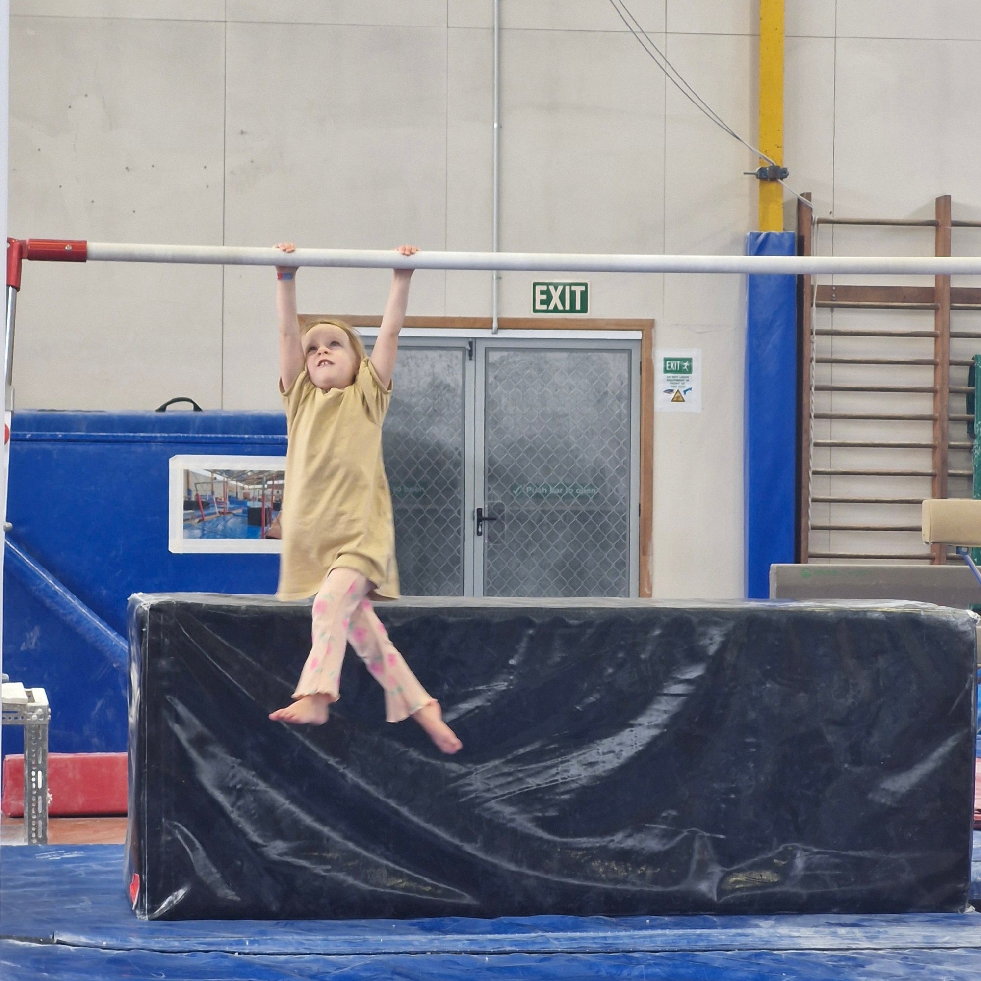Young girls hanging on low bar during a Springboard mini session at gymnastics